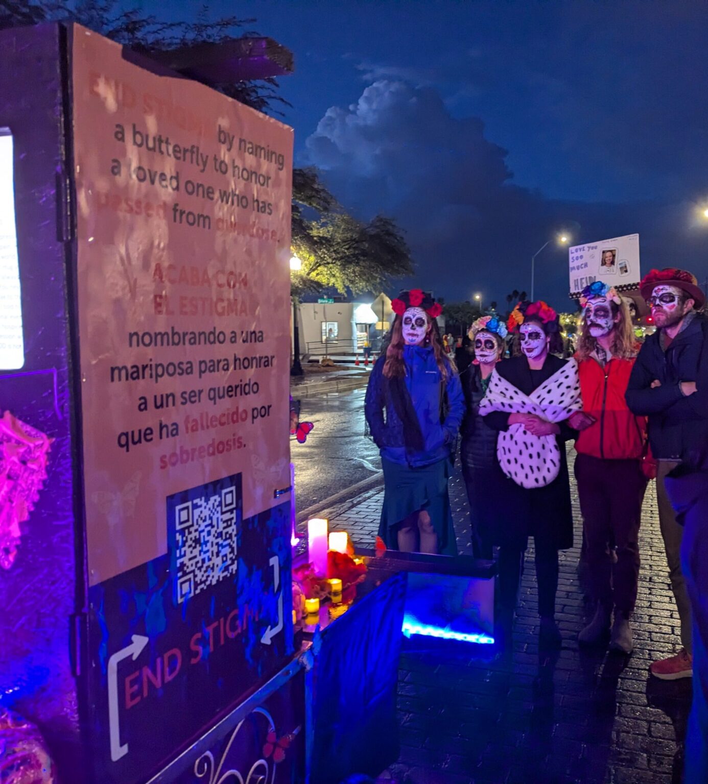 A group attending the All Souls Procession reading the messages of loved ones on the screen.